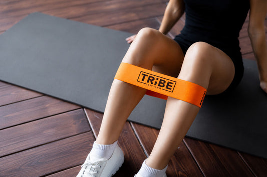Orange fabric resistance band placed above the knees during a seated lower-body workout