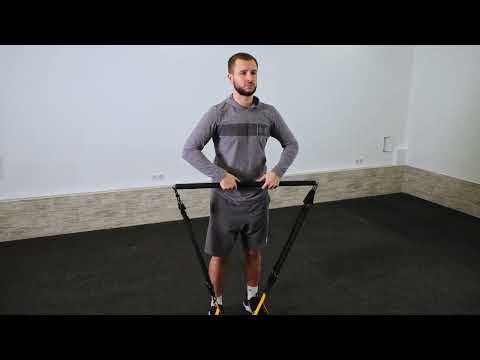 Man using a foam-padded Pilates resistance bar with resistance bands during a standing workout
