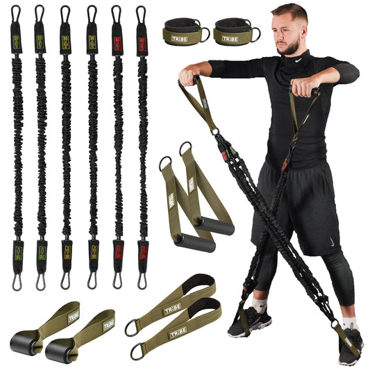 Man using the green Tribe Lifting nylon resistance bands set with handles and foot straps, shown with stackable tube bands, ankle straps, door anchors, and workout attachments for full body strength training.