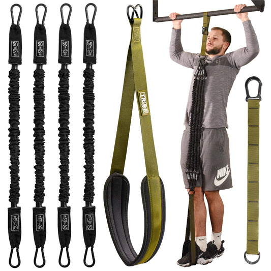 Man using the green Tribe Lifting pull-up assistance set with four 50 lb resistance bands, padded foot strap, adjustable extension strap, and pull-up bar attachment for assisted pull-up training.